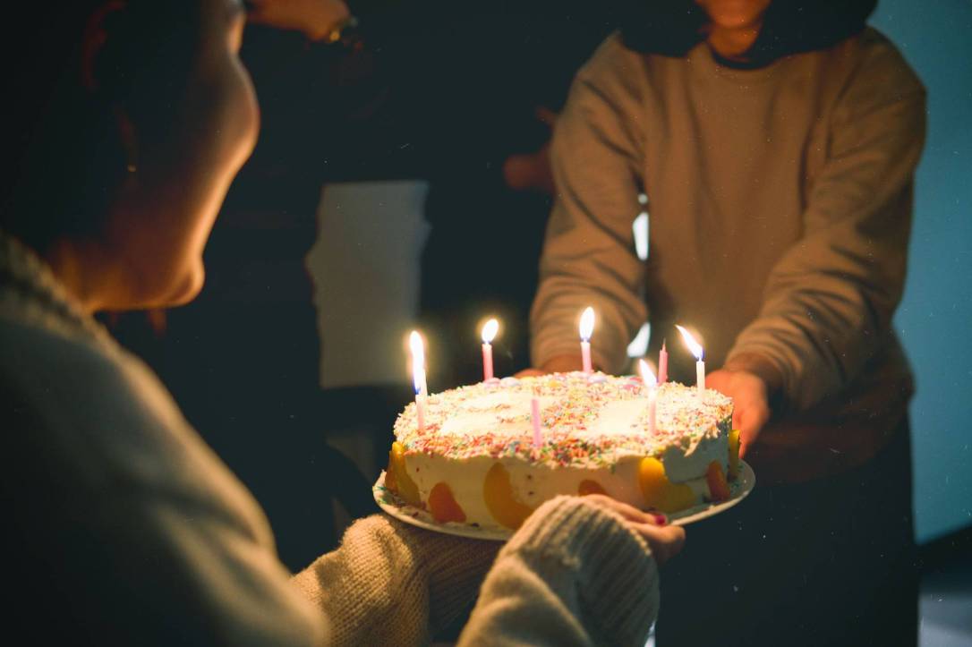 two people holding cake with lit candles